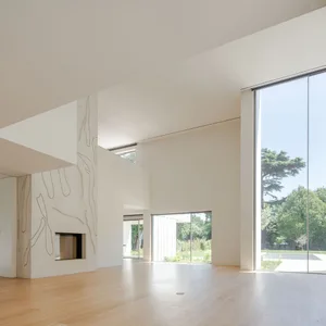 Interior view of a modern living room with white walls and light wooden flooring.