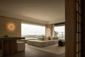 A minimalist living room with a neutral color palette featuring a large sectional sofa, a modern coffee table, and a wall-mou