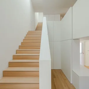 A minimalist staircase with wooden steps against white walls.