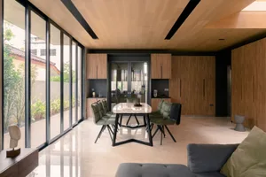 Modern dining room featuring a granite surface table with green upholstered chairs and a dark wooden ceiling.