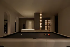Luxury industrial game room with a modern pool table and illuminated shelves