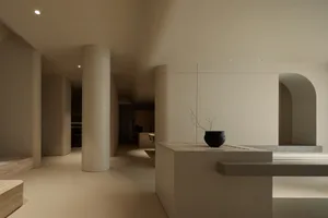 Minimalist interior space with concrete walls and a white vase on a shelf.