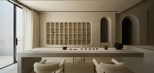 A modern dining room with concrete and wooden elements, featuring a long table with a minimalist setting and an arched doorwa