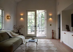 A minimalist living room with neutral-colored walls, a beige sofa, and a white coffee table.