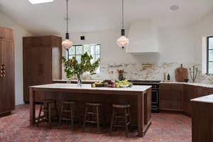 A modern kitchen featuring white marble countertops and backsplash, dark wood cabinets, and a black range with gold accents.