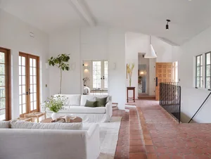 Modern living room featuring terrazzo flooring, white sofas, and large windows.