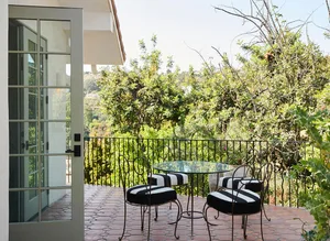 Modern patio with metal table and chairs with black and white striped cushions.