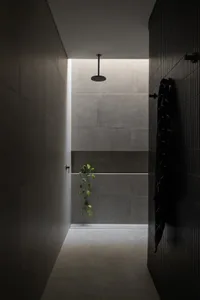 A minimalist bathroom with black tiles and concrete walls.