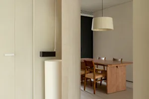 Modern minimalist dining room featuring a wooden table with woven fabric chairs.