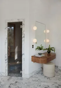 A minimalist interior featuring a marble entrance with a wooden vanity and round lights.