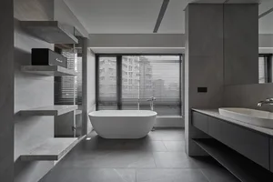 A modern bathroom with concrete flooring, a freestanding bathtub, and minimalist design.
