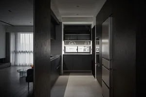 Modern kitchen with black cabinets, wooden floor, and stainless steel appliances.