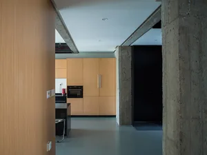 Modern kitchen interior with wooden cabinets and concrete accents.