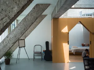An interior design showing a modern living space with concrete walls and exposed beams.