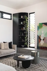 A modern living room featuring concrete walls and plants in corner planters.