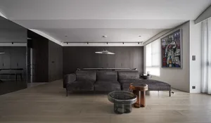 A modern living room featuring dark wooden furniture and a glass and metal coffee table.