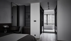 A modern minimalist bedroom with wooden flooring, white walls, and a glass-enclosed bathroom.