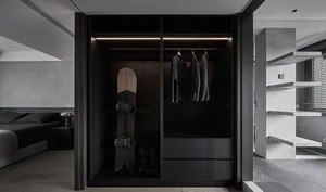 Modern minimalist black closet with a snowboard, jackets, and shoes on a wooden surface.
