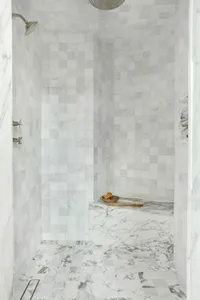 A modern minimalist marble bathroom with marble tiles on the walls and floor.