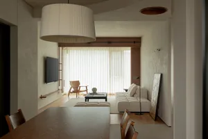 A modern living room with neutral-colored walls and furniture, featuring a white couch, a black and gold floor lamp, and a wo