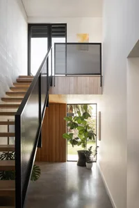 A modern staircase with concrete steps and black railings in an indoor setting with a plant in a vase.