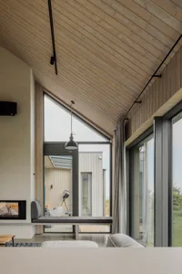 A modern minimalist living room with wood accents and a large window overlooking a natural landscape.