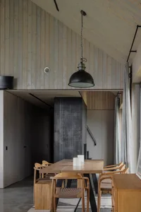 A modern dining room with wooden furniture, featuring a wooden table, chairs, and pendant light.