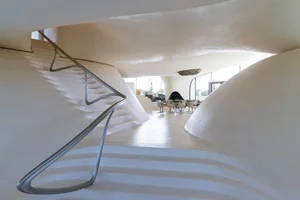 An interior view of a modern house with curved walls made of white concrete.