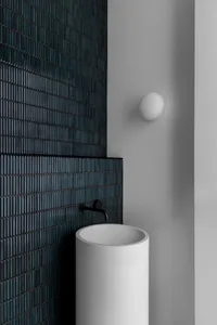 Modern industrial washroom with concrete walls and white pedestal sink with black faucet