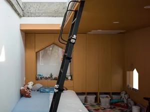 A modern playroom featuring a wooden play space with a ladder leading to a loft.
