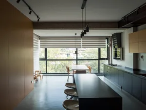 Modern residential kitchen featuring a sleek, minimalist design with exposed concrete flooring and large windows.