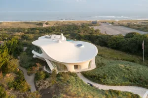 A modern, white stucco and glass residential house with a curved roof and a pool.