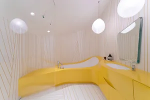 A modern bathroom with a yellow acrylic tub and sink, featuring a wave-shaped design and white pinstriped walls.