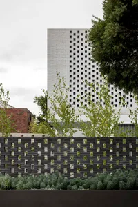 A modern building constructed with brick materials, featuring a grid-like pattern on the facade.