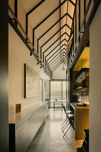 Modern residential entryway with concrete flooring, high ceiling, and industrial-style lighting.