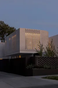 Modern house exterior with a brick wall featuring a perforated pattern and illuminated lights.