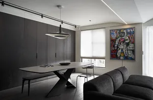 A modern living room featuring a minimalist design with dark wood flooring, glass table top, and metal furniture.
