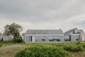 A modern metallic residential home with large windows and a flat roof.
