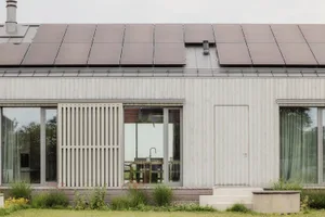 一座現代簡約的住宅建築，外牆採用木質板材，屋頂裝設太陽能板。