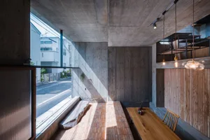 A modern, industrial-style living room with concrete walls and floors, featuring a wooden bench and table.