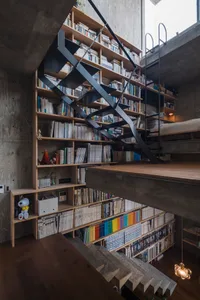 Concrete stairs leading to a floor filled with a large bookshelf filled with books.