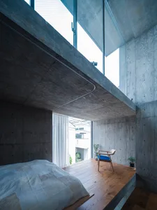 A modern bedroom with concrete walls and a wooden floor.