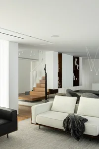 Modern minimalist living room with white couch, black armchair, and wooden accents.