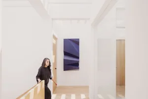 A minimalist interior space with a white wall, wooden floor, and modern artwork