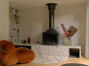 A minimalist living room featuring a marble fireplace and modern furniture.