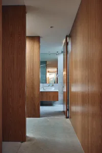 A modern bathroom with wooden panels, a sink, and a mirror.