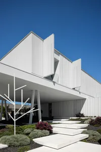 Modern building with white concrete architecture and greenery around it.