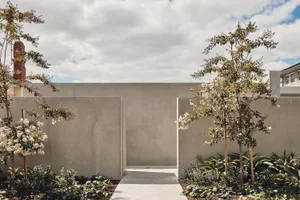 Concrete walls and pathway with flowering trees in a landscaped area.