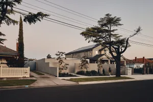 A modern residential house featuring a concrete exterior, brick detailing, and gravel pathway.