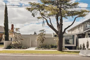 A modern house with a concrete exterior featuring large glass windows.